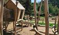 Wooden play structure with woods in background