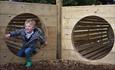 Child climbing through wooden tunnel