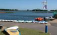 Paddle boards and windsurfing equipment lined up at poole park