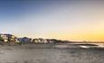 The sunsets over sandbanks beach with the light shining off the houses found along the beach