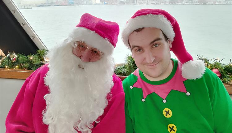 Santa with an elf next to him on a boat