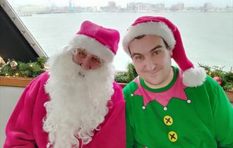 Santa with an elf next to him on a boat