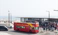 Bournemouth City Sightseeing bus parked outside Boscombe pier with views of the sea