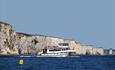 Blue and white pleasure boat near the white cliffs in dorset