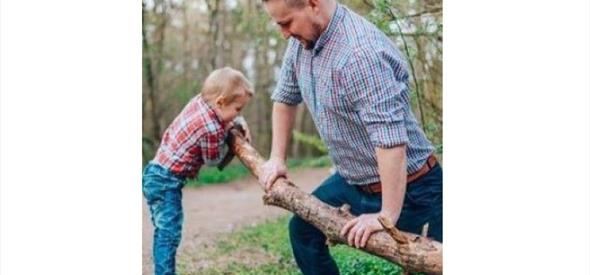 A dad and his young son outdoors holding a stick