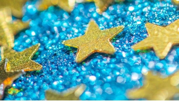 Golden stars laying on a shiny blue background.