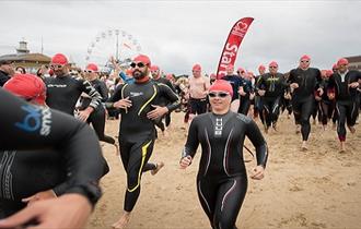 Lady in swim gear running with crowd down the beach