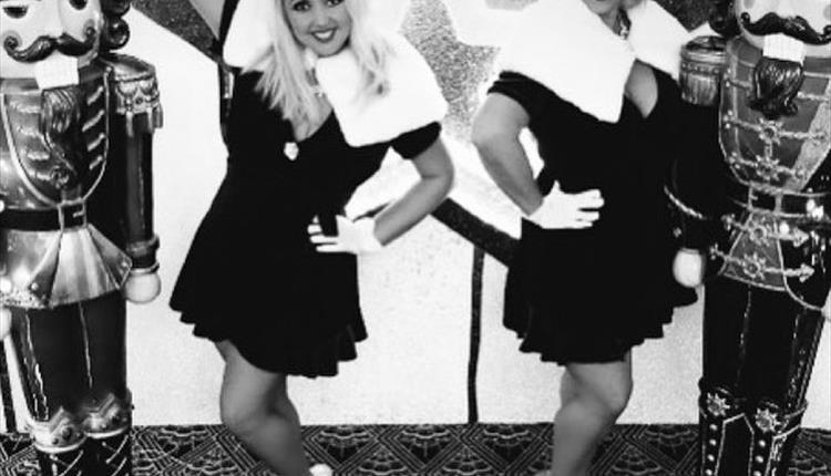 Ladies in black and white with two nutcracker dolls