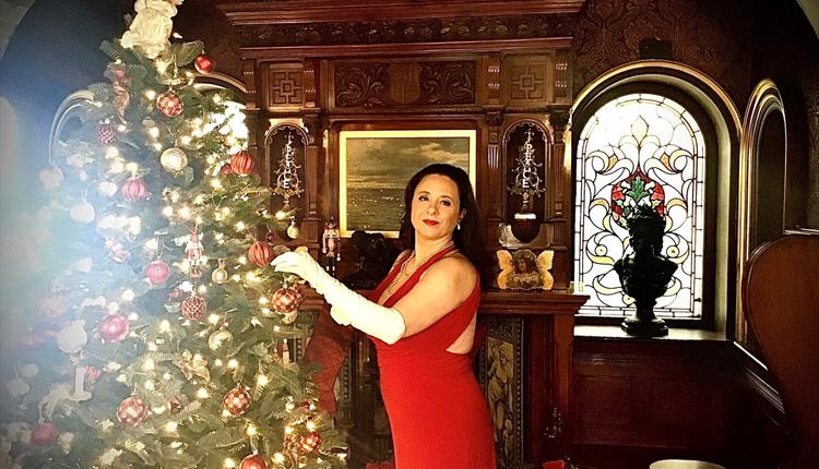 Woman in red dress and glamourous hair by Christmas Tree