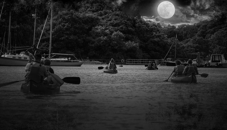 People kayaking on river at night