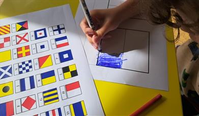 A child colouring in flag sheets to spell out a name