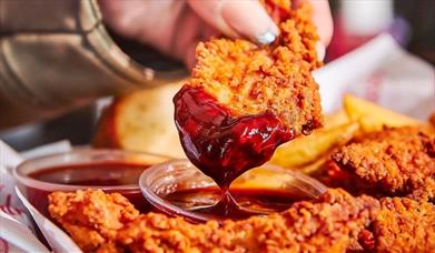 Chicken tenders from Slim Chickens being dipped into a sauce