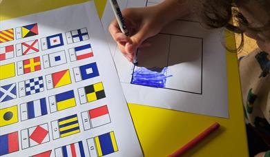 A boy colouring in flag sheets to spell out his name