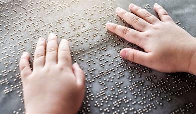 A person's hands as they read braille