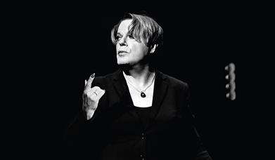 A black and white picture of Eddie Izzard on stage.