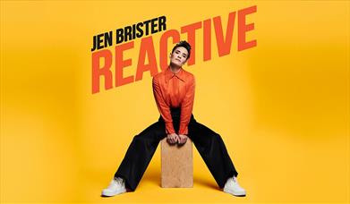 Comedian Jen Brister sat on a wooden box.