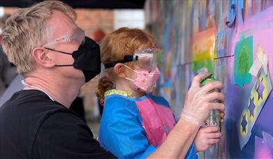 A child and adult spray painting