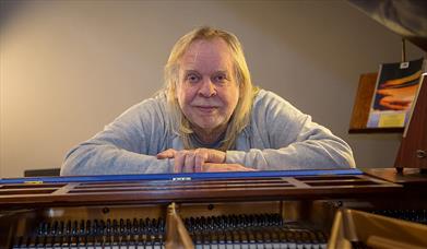 Photograph of Rick Wakeman sat at a piano