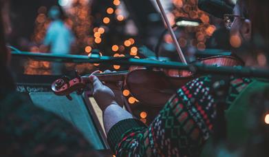 Stock photograph showing a person in a Christmas jumper playing the violin