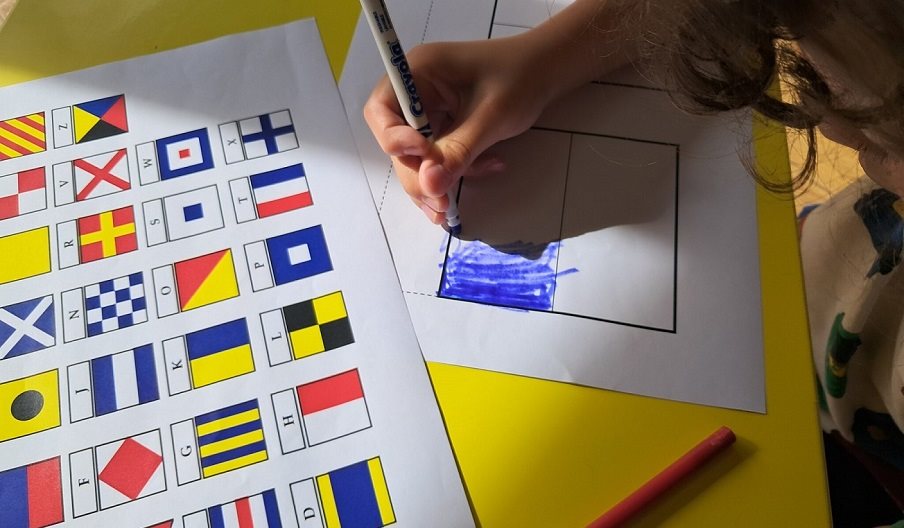 A child colouring in flag sheets to spell out a name