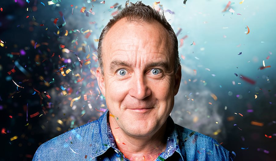 Head and shoulders shot of comedian Jimeoin with confetti around him.
