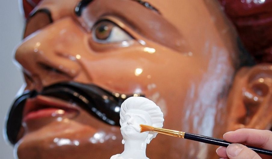 Photograph of a 3D printed miniature and the figurehead on which it was based.