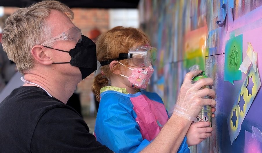 A child and adult spray painting