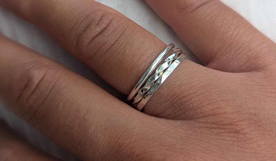 A close up of a person's hand, wearing stacking rings