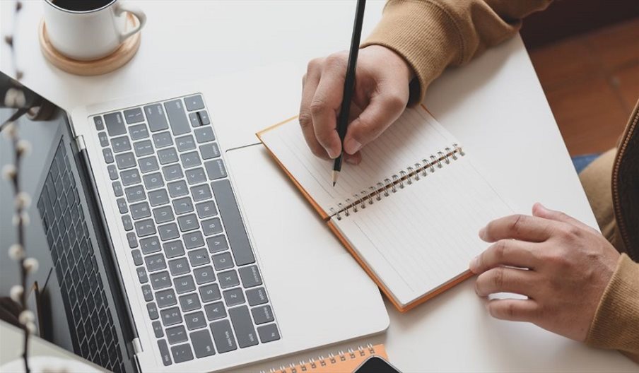 Stock photo of someone writing at a laptop