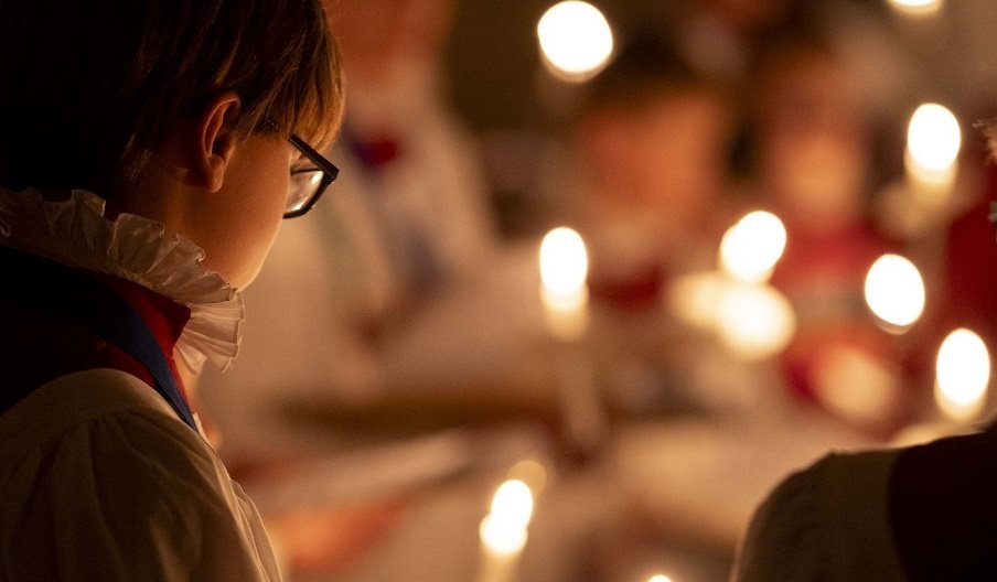 A chorister at Portsmouth Cathedral lit by candles.