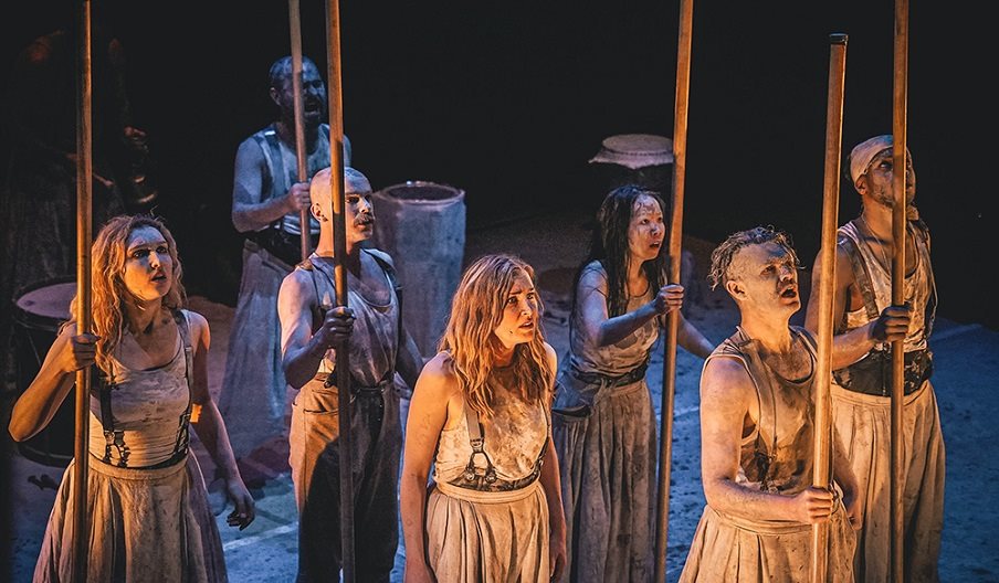 A group of seven actors dressed in rags most holding sticks. From a production of Macbeth.