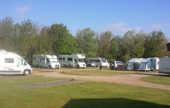 Touring caravans and motorhomes lined up at Kingfisher Caravan Park