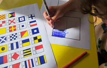 A boy colouring in flag sheets to spell out his name