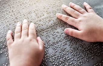 A person's hands as they read braille