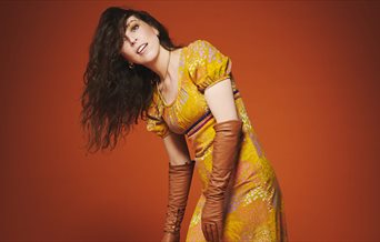 Bridget Christie in a gold dress for the promotional shot of her latest tour: Jacket Potato Pizza