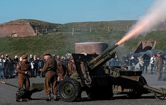 Photograph showing a large gun being fired on the Parade Ground at Fort Nelson
