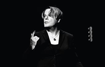 A black and white picture of Eddie Izzard on stage.