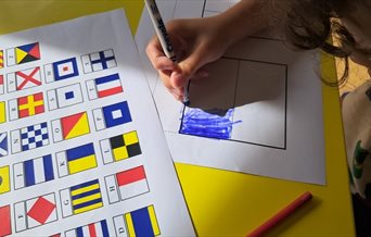 A child colouring in flag sheets to spell out a name