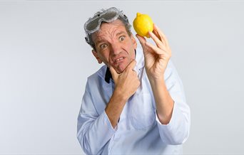Photograph of comedian Henning Wehn looking at a lemon