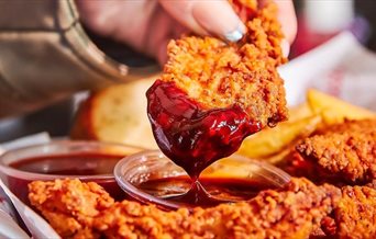 Chicken tenders from Slim Chickens being dipped into a sauce