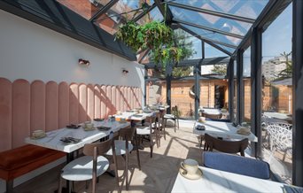 Dining tables set in the Glasshouse of The Garden Restaurant