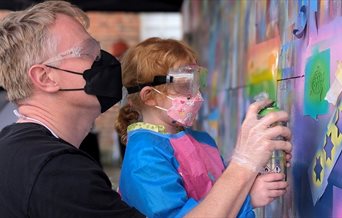 A child and adult spray painting