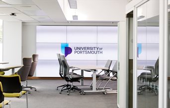 Office space with the University of Portsmouth logo on a window behind