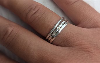 A close up of a person's hand, wearing stacking rings