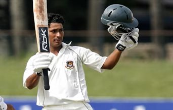 A cricket player holding his helmet and bat.