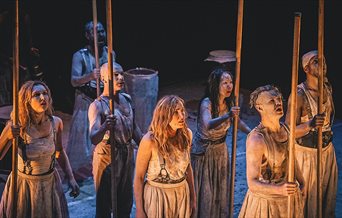 A group of seven actors dressed in rags most holding sticks. From a production of Macbeth.