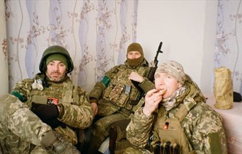 A photograph of three Ukrainian soldiers in military fatigues during downtime.