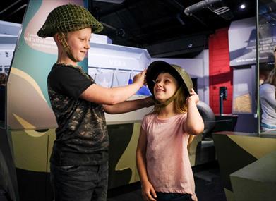 Children trying on helmets at the D-Day Story