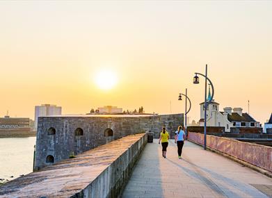 People walking along the fortifications of Old Portsmouth at sunset