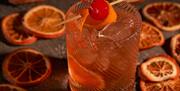 A cocktail at the sky bar in a tumbler-style glass, with orange segments all around.